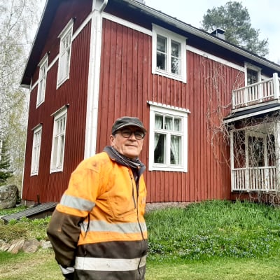 En man framför ett rött hus.