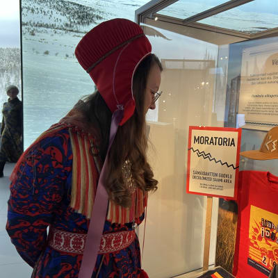 Anniina Turunen katselee itse suunnittelemaansa poronnahkalippistä Saamenmuseo Siidan näyttelyssä 1.6.2022