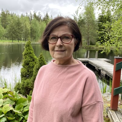 Suomen kielen emeritaprofessori Kaisa Häkkinen seisoo lammen rannalla.