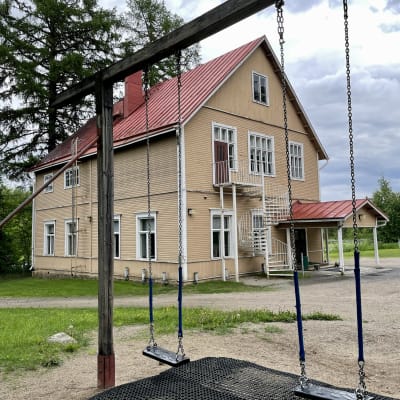 Vanha puinen kaksikerroksinen harjakattoinen koulurakennus.