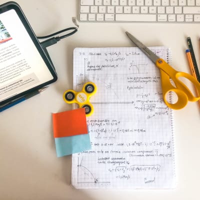 Studiematerial och ett anteckningsblock med matematiska formler på ett skrivbord.