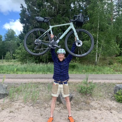 En man står och håller en cykel ovanför sitt huvud.