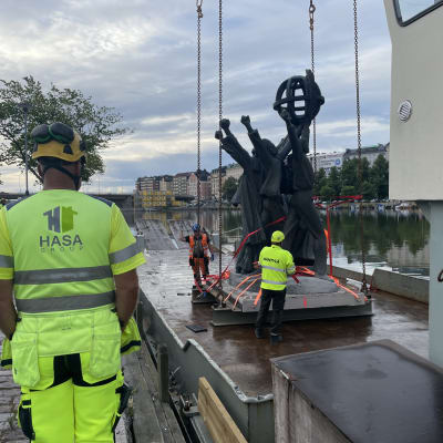 Statyn Världsfreden flyttas från Hagnäs och lyfts ombord på en pråm med hjälp av lyftkran. 