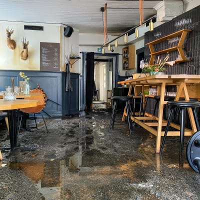 En förstörd restaurang med vatten och sotsörja på golvet. 