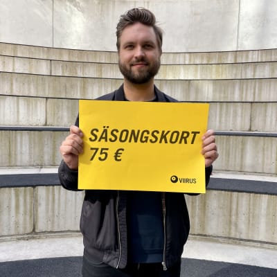 En leende mörkhårig man med ett guld plakat.