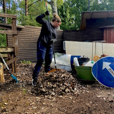 En kvinna som krattar löv.
