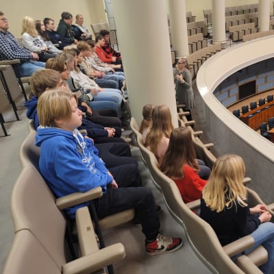 Kyrkbackens skolas elever sitter i plenisalen i riksdagen