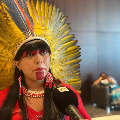 Kvinna och kongressledamot från ursprungsbefolkning i Amazonas, med huvudbonad med stora gula fjädrar