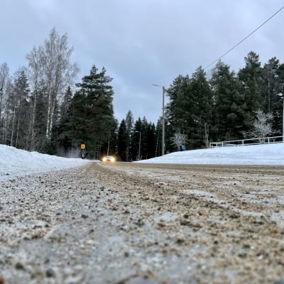 Auto tulossa hiekoitettua jäistä teitä pitkin. 