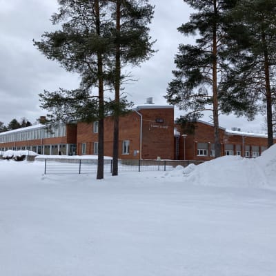 Iso koulurakennus talvisessa maisemassa Simon kunnassa.