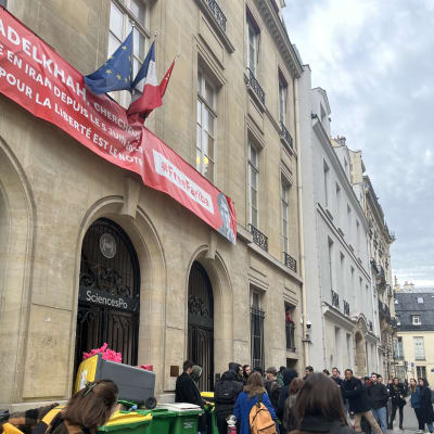 Folk har samlats utanför en ingång till ett hus i Paris.