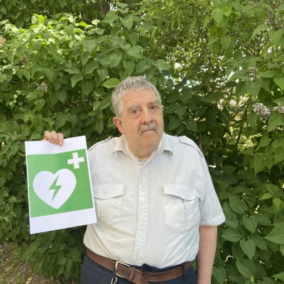 En äldre man med en bild på symbolen för hjärtstartare.