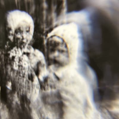 Epäselvä kuva kahdesta lapsihahmosta, valokuva tietokoneruudun läpi vanhasta lasinegatiivista.