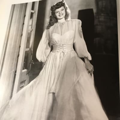 Rita Hayworth i klädd en vit chiffongklänning.
