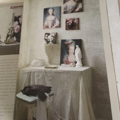 Ett bord med vit spetsduk och en madonnastaty och gamla kvinnoporträtt.