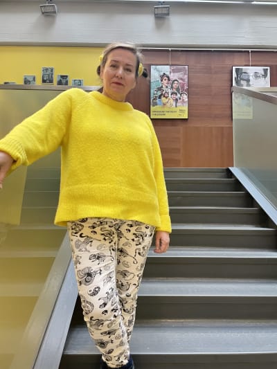 Pia Puu Oksanen står i en gul tröja i trappan på Amnestys kontor i Helsingfors.