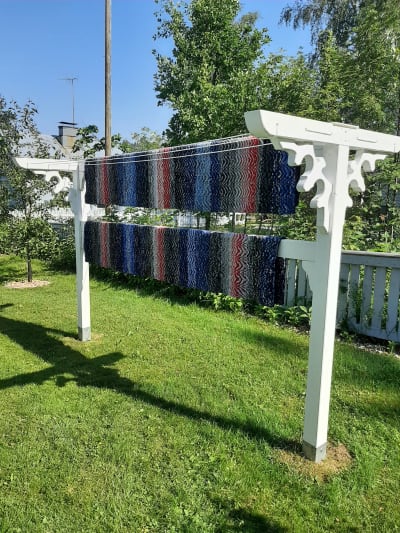 Två mattor som hänger på en vit torkställning av trä.