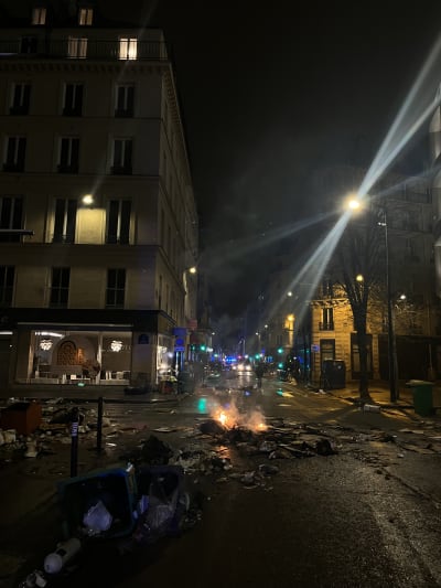 En mörk gata i Paris, sopor utspridda över gatan.