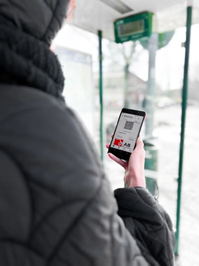 En person ser på sin telefon, som visar en nätsida med en bussbiljett.