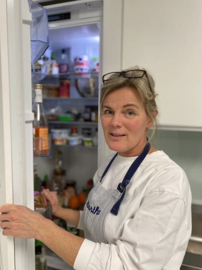 Elisabeth Eriksson som är hushållsrådgivare på Marthaförbundet. Hon står vid ett belamrat kylskåp som har öppen dörr. I kylskåpet skymtar alla möjliga produkter. 