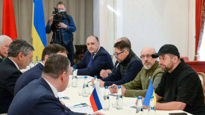 Förhandlingar mellan en rysk delegation till vänster och en ukrainsk till höger.