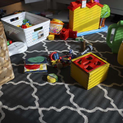 Färggranna leksaker ligger utspridda på en svartvit matta.