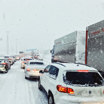 Liikenne seisoo lumisateessa Kolmostiellä. 