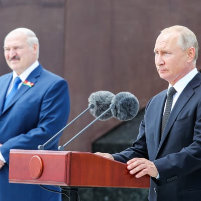 Aljksandr Lukašenka ja Vladimir Putin seisovat Rževissä muistomerkin edustalla. Putinilla on edessään puhujanpönttö ja kaksi mikrofonia. Taustalla näkyy sotilas paraatiunivormussa.
