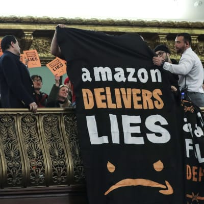 "Amazon levererar lögner" står det på banderollen som vecklades ut från balkongen under höringen med Amazons ledning i New York Stadshus.