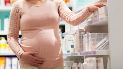 Gravid kvinna tittar på produkter i ett apotek.