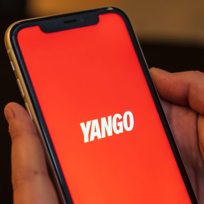 En hand som håller i en telefon där taxiappen Yango syns.