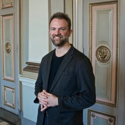 En man står framför utsirade och målade dörrar