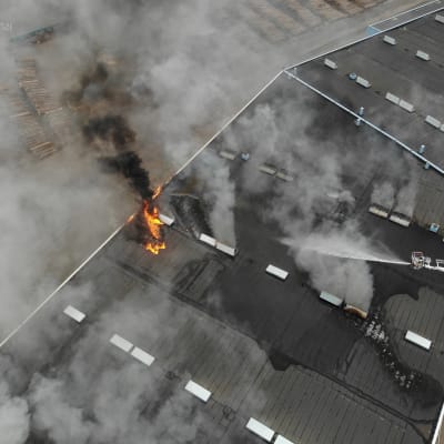Pelastuslaitos sammuttaa tulipaloa satamahallissa