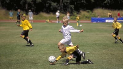 Två småpojkar spelar fotboll.