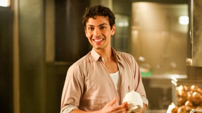 Karaktären Angelo står i köket och torkar sina händer.