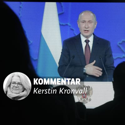 Vladimir Putin som håller tal visas på en skärm framför en publik som syns som skuggor.