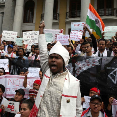 Bild från demonstration i Bangalore i Indien mot. På bilden syns en vitklädd man i förgrunden som räcker upp sin knutna näve ovanför hvuudet.