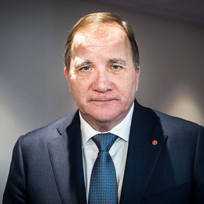 En man i kostym och slips tittar in i kameran.