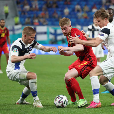 Kevin De Bruyne jalkapallon EM-kisoissa 2021 Jere Urosen ja Rasmus Schüllerin pihdeissä.