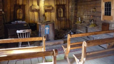 ett litet kapell  inrymt i en byggnad som fungerat som ladugård. Träbankar, och kors på väggen  gjort av gamla stockar.