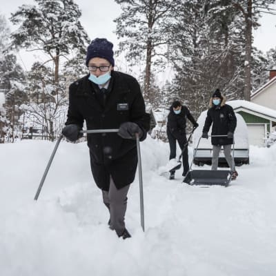Harlan Stevens ja kaksi muuta kirkon jäsentä kolaamassa lunta omakotitalon pihatiellä. 