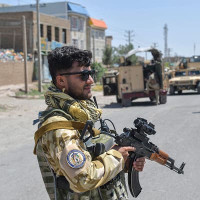 En soldat med pistol bevakar en stad i Afghanistan.