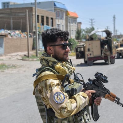 En soldat med pistol bevakar en stad i Afghanistan.