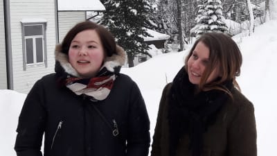 Nora Marie och Katriina på snöklädd backe, utanför trähus i Tromsö.
