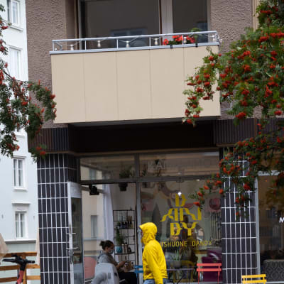 En man i gul regnrock promenerar i regn i Berghäll i Helsingfors. 