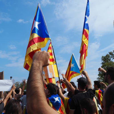 Katalanska flaggor och knytnävar i luften under en demonstration i Barcelona