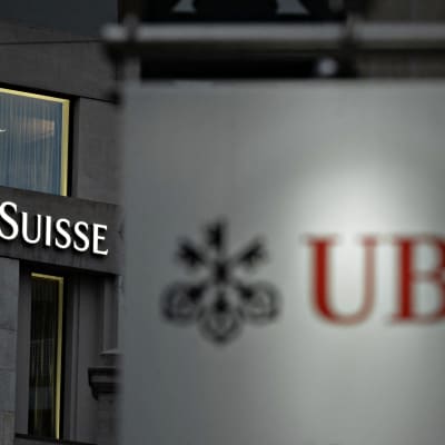 Vredit Suisses och UBS logotyper fotograferade bredvid varandra i schweiziska Geneve.