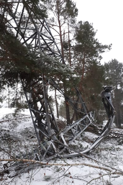 Förvriden metall ligger på en snöig mark efter att masten till en högspänningsledning gått av i en vinterstorm.