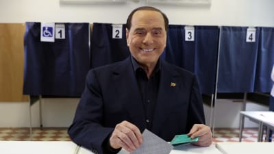Silvio Berlusconi röstar i en folkomröstning i Milano med ett brett leende på läpparna.