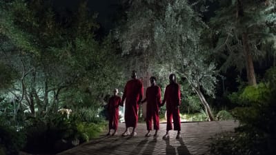 En rödklädd familj ser hotfull ut där alla fyra står hand i hand.